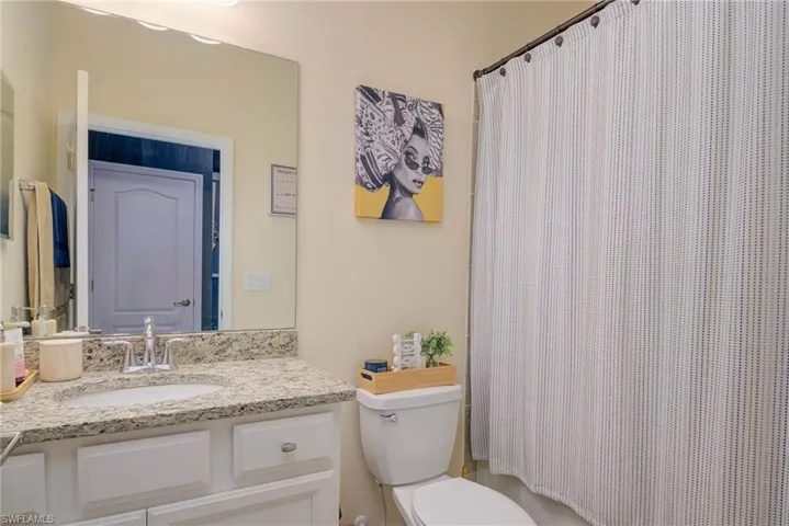 Full bathroom featuring a single vanity with a granite-style countertop, undermount sink, and chrome faucet