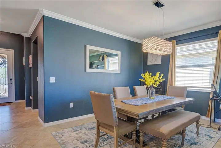 Dining area with crown molding, a rectangular crystal chandelier, tile flooring, and a window with blinds