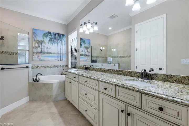 Bathroom featuring double vanity, a walk in shower, ornamental molding, a bath, and light tile patterned floors