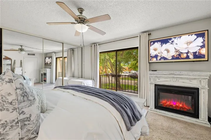 Carpeted bedroom featuring a closet, ceiling fan, a textured ceiling, and access to outside