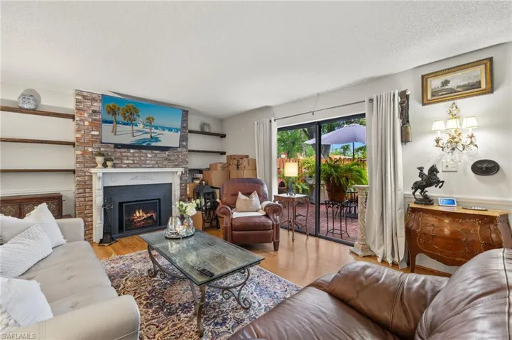Living room featuring light hardwood / wood-style floors, a textured ceiling, a fireplace, and brick wall