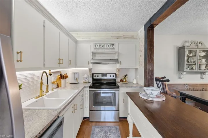 Kitchen featuring backsplash, sink, hardwood / wood-style flooring, white cabinetry, and appliances with stainless steel finishes