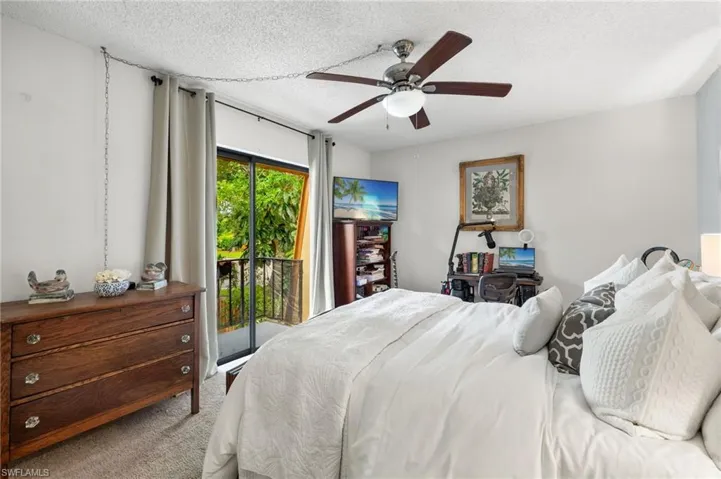 Carpeted bedroom with a textured ceiling, ceiling fan, and access to exterior