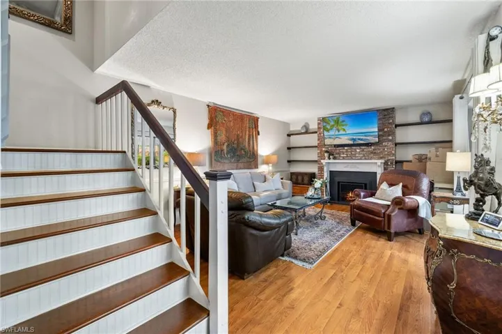Living room with light wood-type flooring, a textured ceiling, brick wall, and a brick fireplace