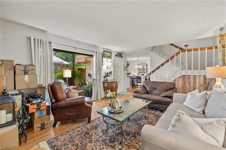 Living room featuring a notable chandelier, wood-type flooring, and a textured ceiling