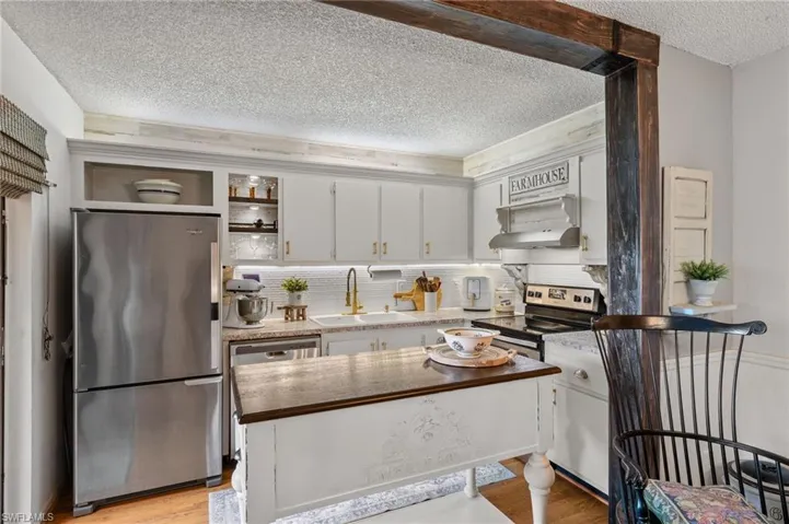Kitchen featuring tasteful backsplash, light wood-type flooring, a textured ceiling, sink, and appliances with stainless steel finishes