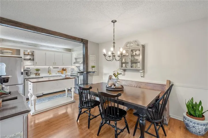 Dining area with a notable chandelier, light hardwood / wood-style flooring, and a textured ceiling