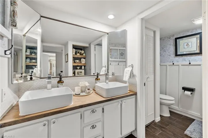 Bathroom featuring dual bowl vanity, hardwood / wood-style floors, tasteful backsplash, and toilet