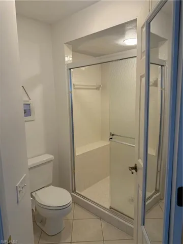 Full bath with a shower stall and light tile patterned floors