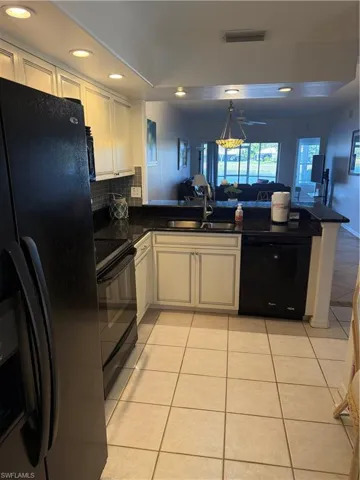 Kitchen with fridge, light tile patterned floors, open floor plan, a peninsula, and dishwasher