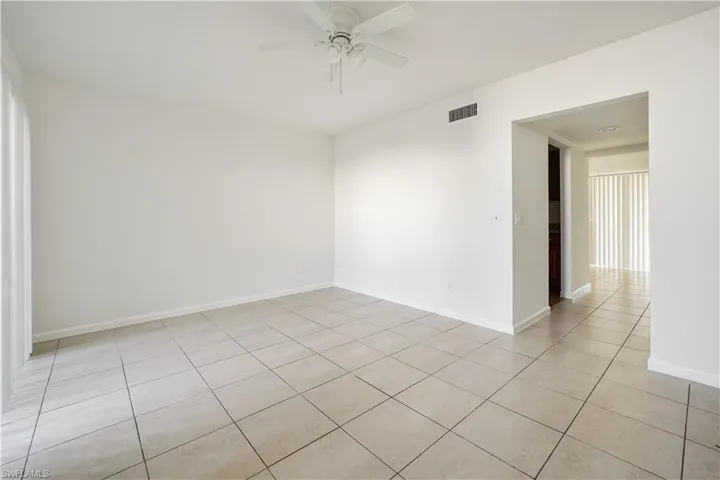 Spacious room with light-toned tiled flooring, white painted walls, and a ceiling fan