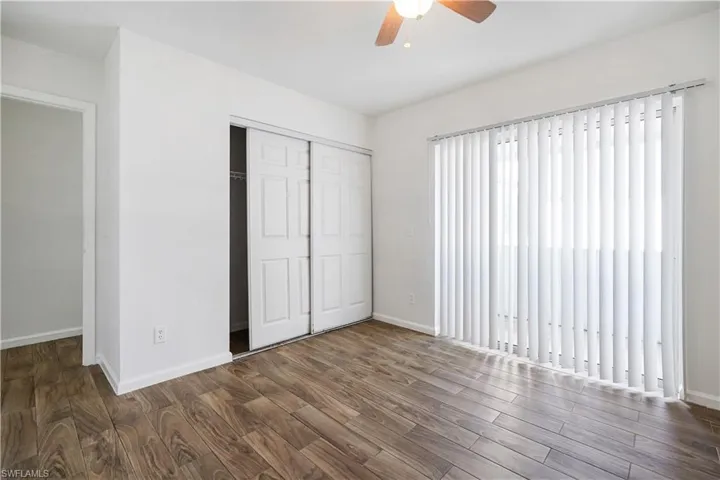 Spacious room featuring wood-finish flooring, white walls, and a ceiling fan