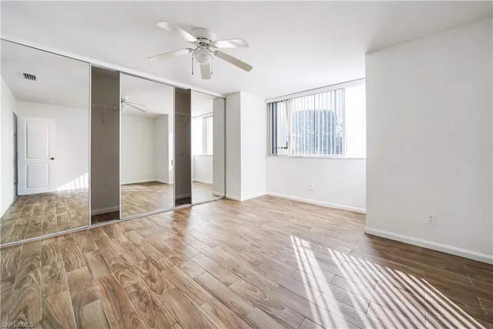 Room featuring wood-finish flooring, a ceiling fan, and white walls