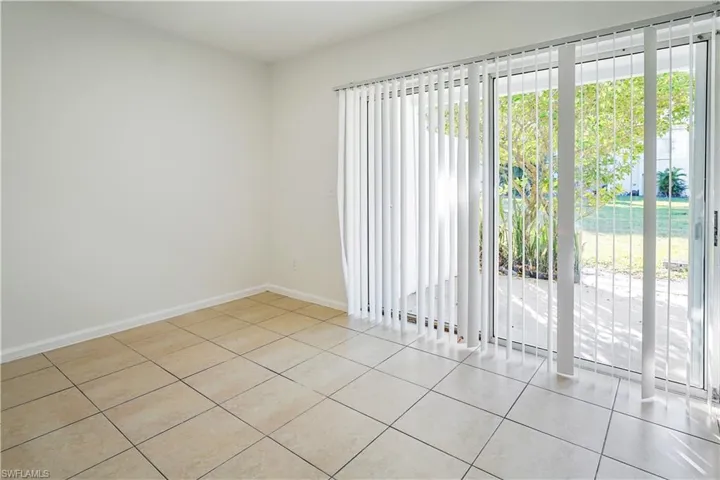 Sliding glass doors featuring vertical blinds, tile flooring, and a private patio