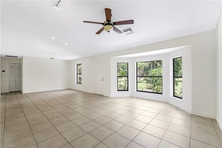 Unfurnished room featuring light tile patterned flooring, ceiling fan, and vaulted ceiling