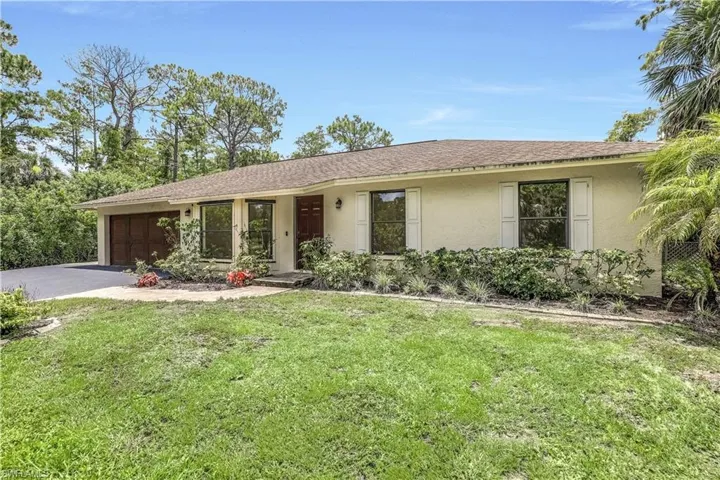 Single story home featuring a garage and a front lawn