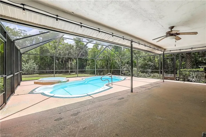 View of swimming pool with a patio, an in ground hot tub, ceiling fan, and glass enclosure