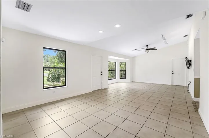 Unfurnished room featuring plenty of natural light, ceiling fan, vaulted ceiling, and light tile patterned floors