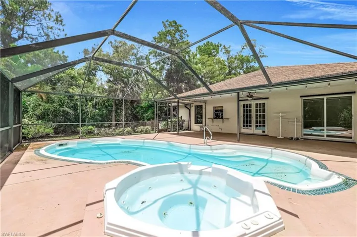 View of swimming pool with a patio area, ceiling fan, an in ground hot tub, french doors, and glass enclosure