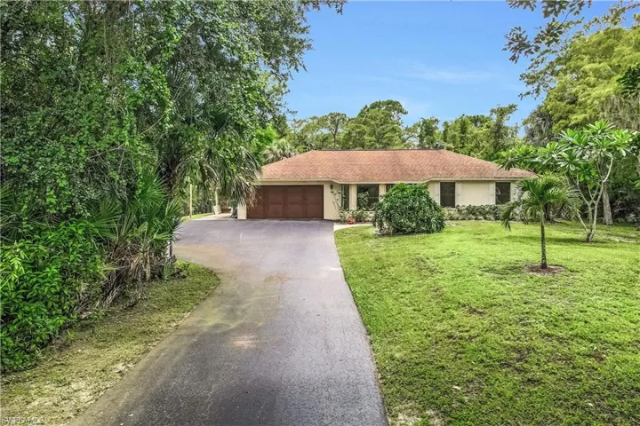 Ranch-style home featuring a garage and a front lawn