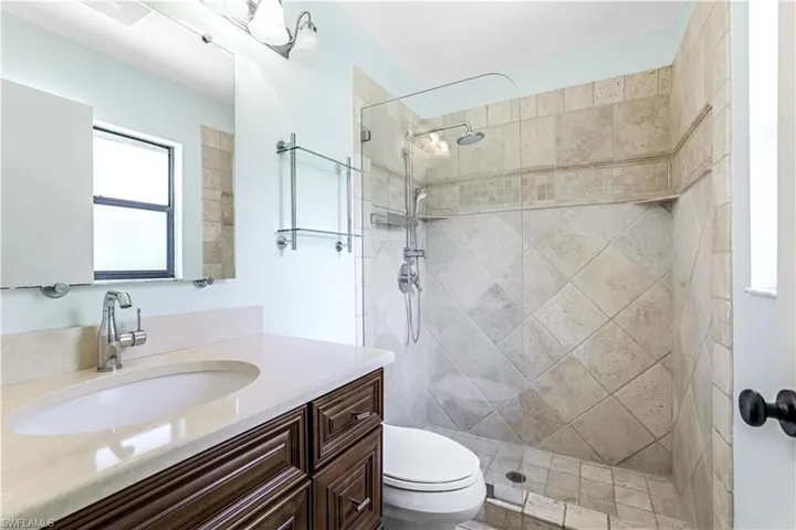 Bathroom with vanity, tiled shower, and toilet