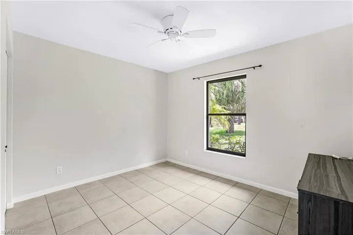 Tiled spare room featuring ceiling fan