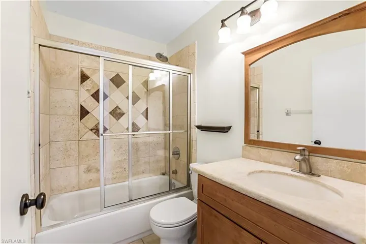 Full bathroom featuring vanity, tile patterned flooring, bath / shower combo with glass door, and toilet