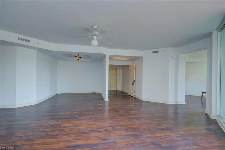 Spare room with dark wood-type flooring and ceiling fan