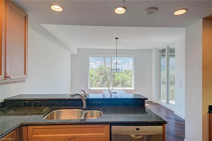 Kitchen featuring recessed lighting, dark stone counters, dishwasher, dark wood-style flooring, and a chandelier