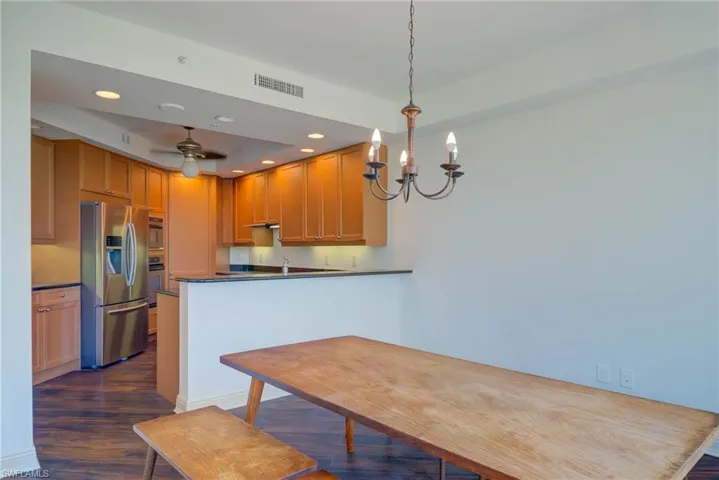Kitchen featuring dark wood-style floors, recessed lighting, stainless steel fridge, a peninsula, and hanging light fixtures