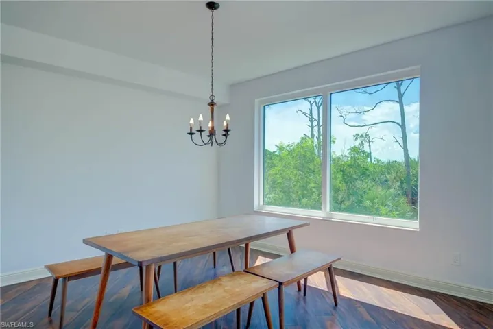 Breakfast Room with dark wood flooring and a chandelier. Entry from Entry and Sliders to Large Back Balcony.