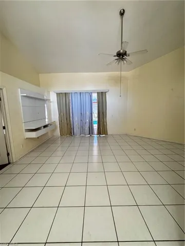Spare room featuring ceiling fan, light tile patterned floors, and lofted ceiling