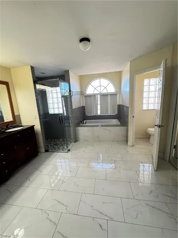 Full bathroom with a garden tub, a stall shower, light marble finish floors, and plenty of natural light