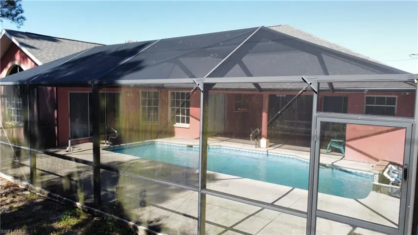 Back of house with a lanai, an outdoor pool, and a patio area