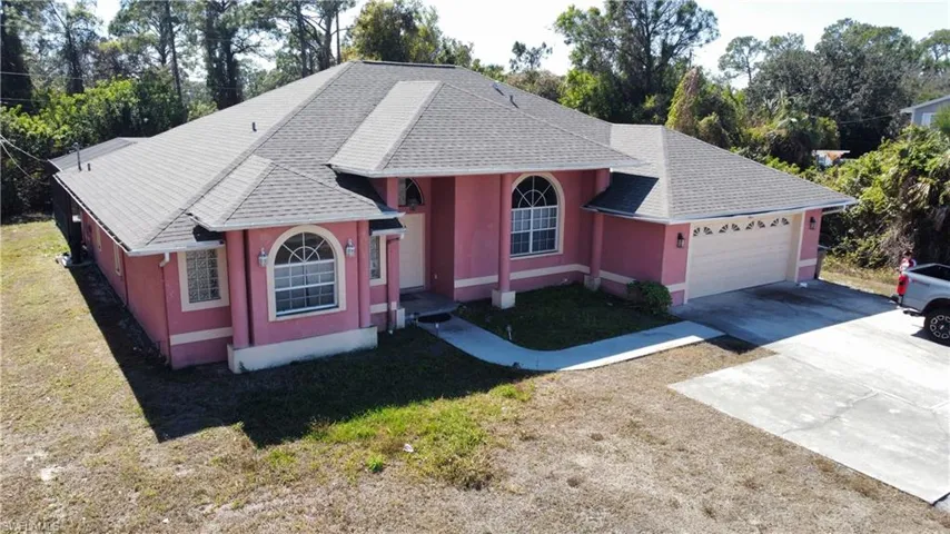 View of front of house with a shingled roof, concrete driveway, an attached garage, stucco siding, and a front yard