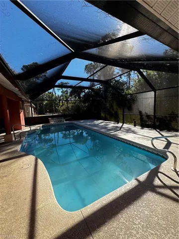 Swimming pool featuring a sunroom, glass enclosure, and a patio