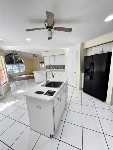 Kitchen with white cabinets, a kitchen island with sink, light tile patterned floors, open floor plan, and light countertops