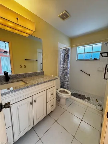 Full bath with vanity, a shower stall, and light tile patterned floors