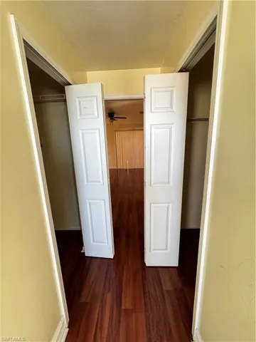 Corridor featuring dark wood-style floors and baseboards