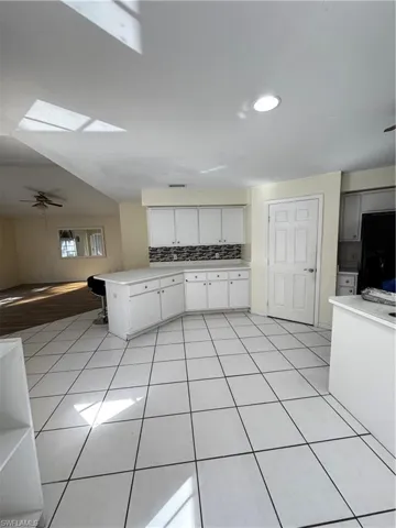 Kitchen featuring light countertops, white cabinetry, a peninsula, a ceiling fan, and open floor plan
