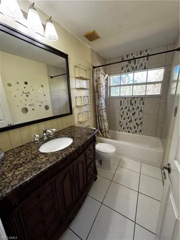 Bathroom with shower / bath combo with shower curtain, vanity, and light tile patterned flooring