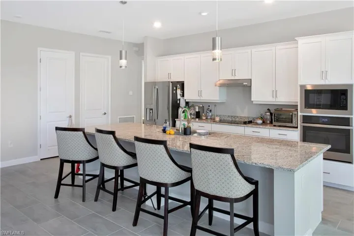 Kitchen featuring white cabinetry, appliances with stainless steel finishes, a breakfast bar, and recessed lighting