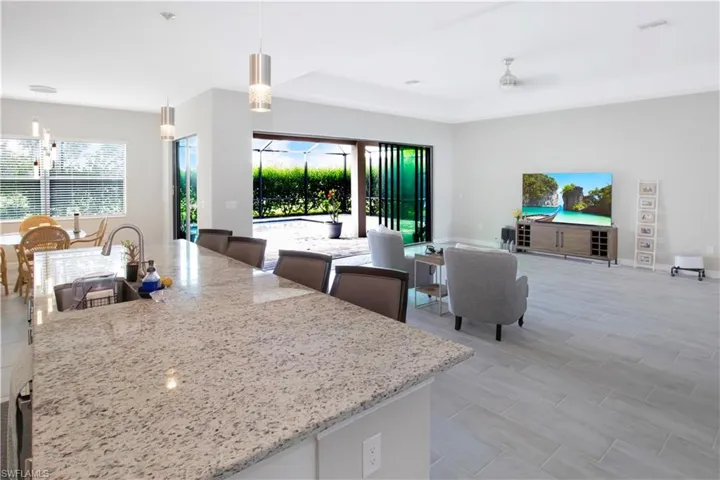 Kitchen featuring hanging light fixtures, white cabinets, a kitchen island with sink, and plenty of natural light