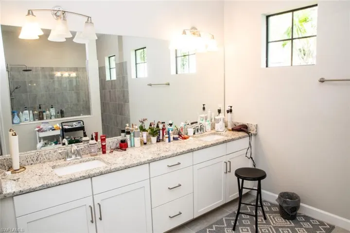 Bathroom with double vanity, walk in shower, and dark tile patterned floors