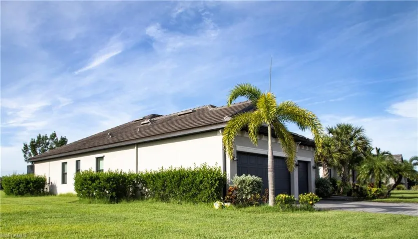 View of side of home featuring a lawn, a garage, stucco siding, and driveway