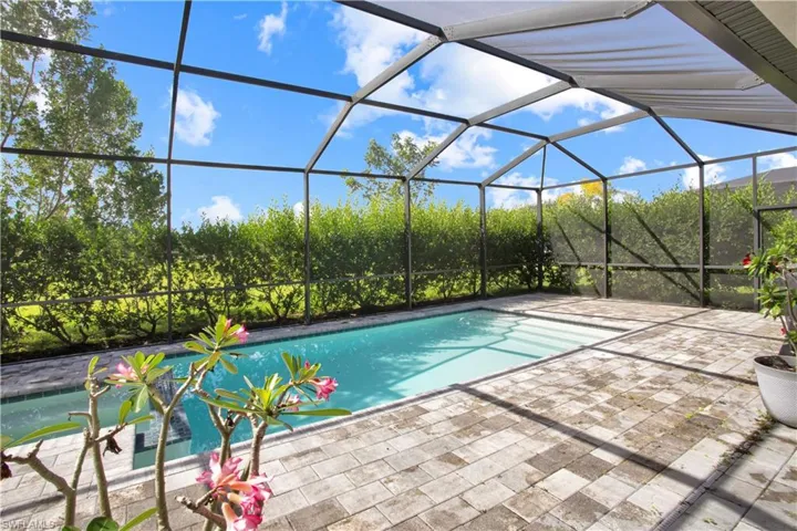 Outdoor pool featuring glass enclosure, a sunroom, and a patio area