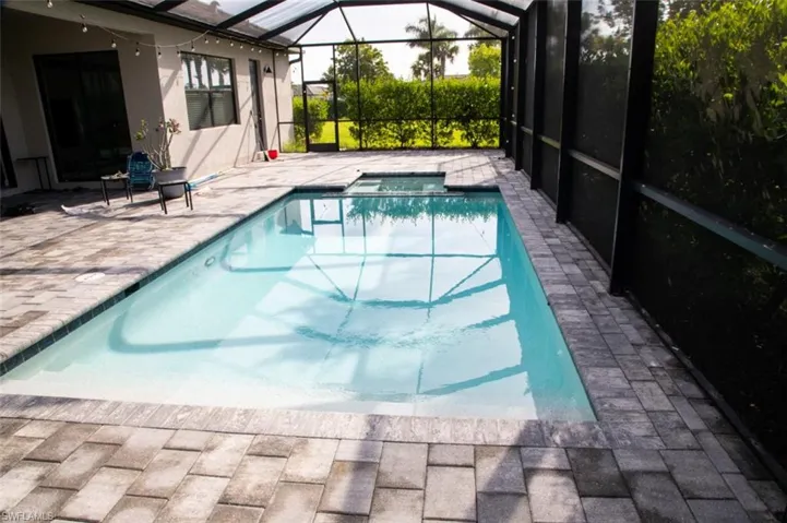 View of pool with a patio, a sunroom, glass enclosure, and a pool with connected hot tub