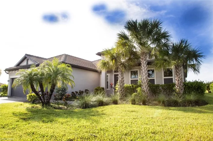 View of front facade featuring a garage, stucco siding, a front yard, and driveway
