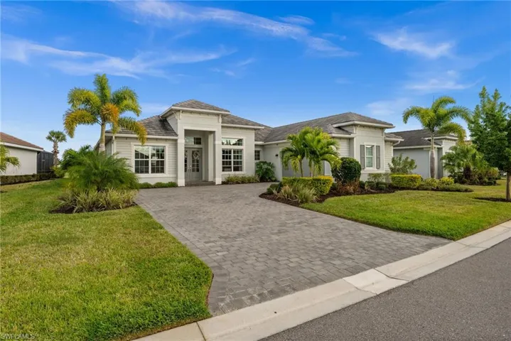 View of front of property featuring a front lawn, decorative driveway, and stucco siding