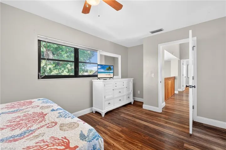 Bedroom featuring wood-finish flooring, a ceiling fan, and a large window with exterior views